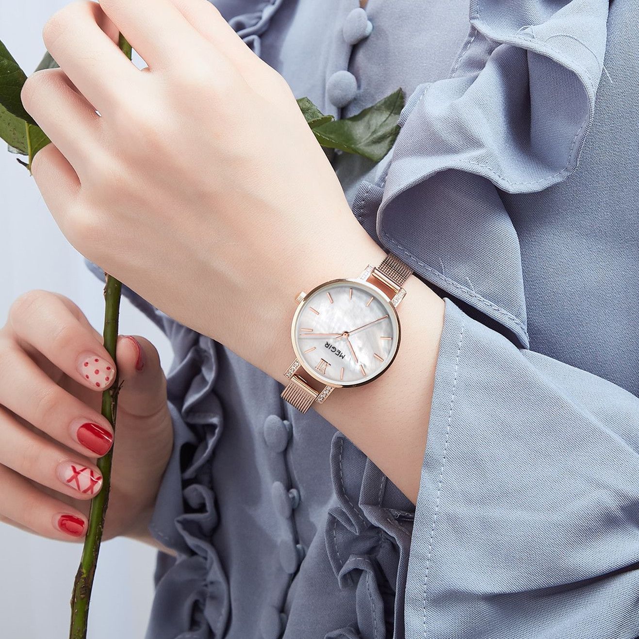 MEGIR 7002 quartz watch on the wrist, rose-gold mesh bracelet and white mother-of-pearl dial, holding a rose
