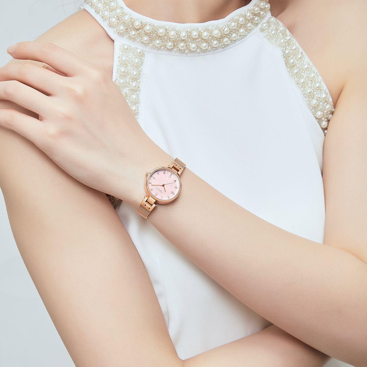 MEGIR 7025 quartz watch on the wrist, pink dial and rose-gold mesh bracelet, arm crossed