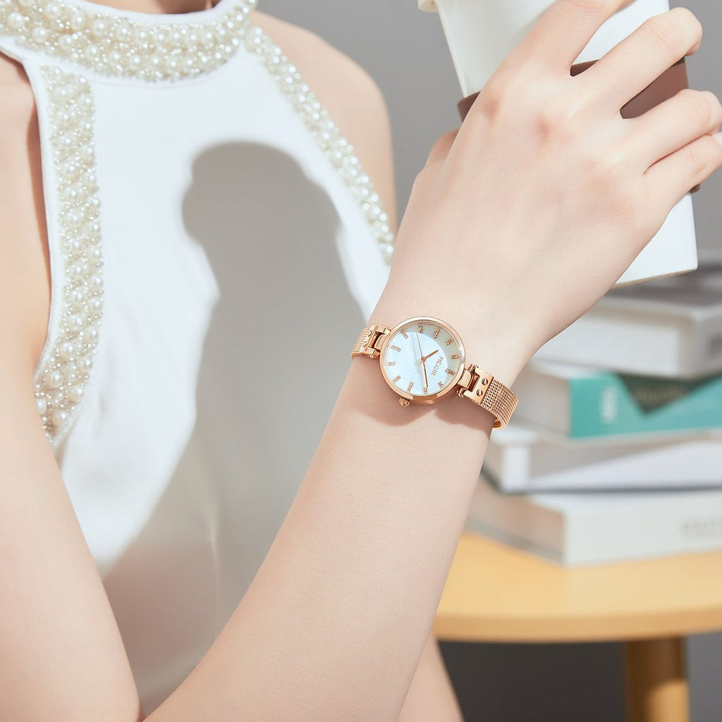 MEGIR 7025 quartz watch on the wrist, white dial and rose-gold mesh bracelet, with books