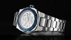 MEGIR 8606 skeleton automatic watch, silver case, blue bezel and steel bracelet, angled beauty shot