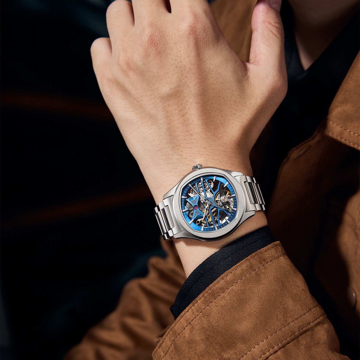 MEGIR 9204-5 skeleton automatic watch on the wrist, blue openwork dial and steel bracelet, with a tan jacket