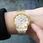 MEGIR 96002 two-tone automatic watch shown on a wrist, white dial and gold bezel, blue background