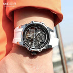 MEGIR men's skeleton automatic tourbillon watch with white strap on wrist with orange shirt