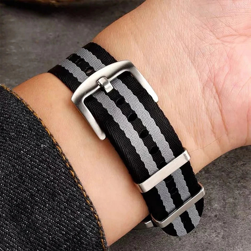 Wrist shot of Pagani Design nylon watch strap with black and grey stripes, 20mm width, showing metal buckle on a wrist