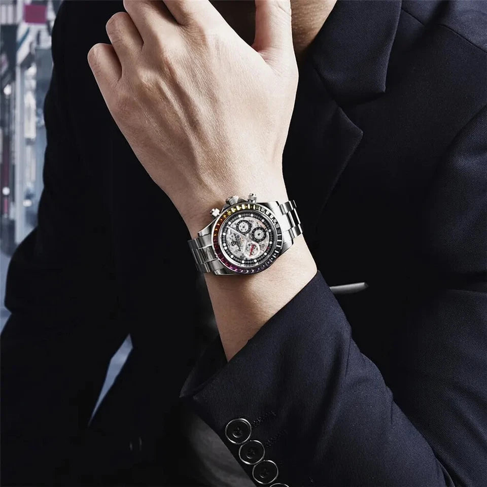 Wrist shot of Pagani Design PD-1653 automatic mechanical chronograph watch with skeleton dial, black tachymeter bezel, and polished stainless steel bracelet, worn on a person's wrist with a dark suit.
