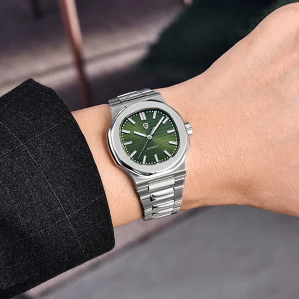 Wrist shot of Pagani Design PD-1728 mechanical automatic watch with green dial, stainless steel case and integrated bracelet, worn on a wrist with a dark jacket and blurred background.
