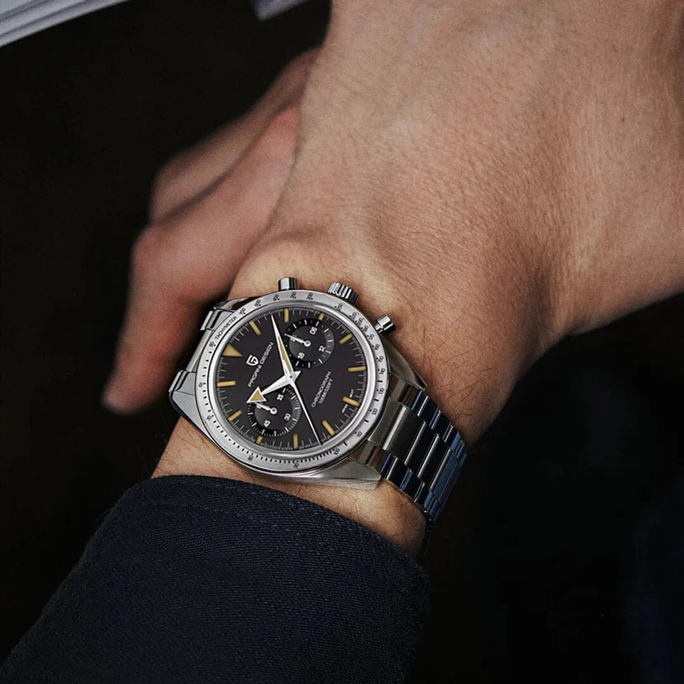 Wrist shot of Pagani Design PD-1766 men's moon quartz chronograph watch with a black dial, gold-tone markers, chronograph subdials, tachymeter bezel, stainless steel case, and matching stainless steel bracelet, worn on a wrist in a dark suit.