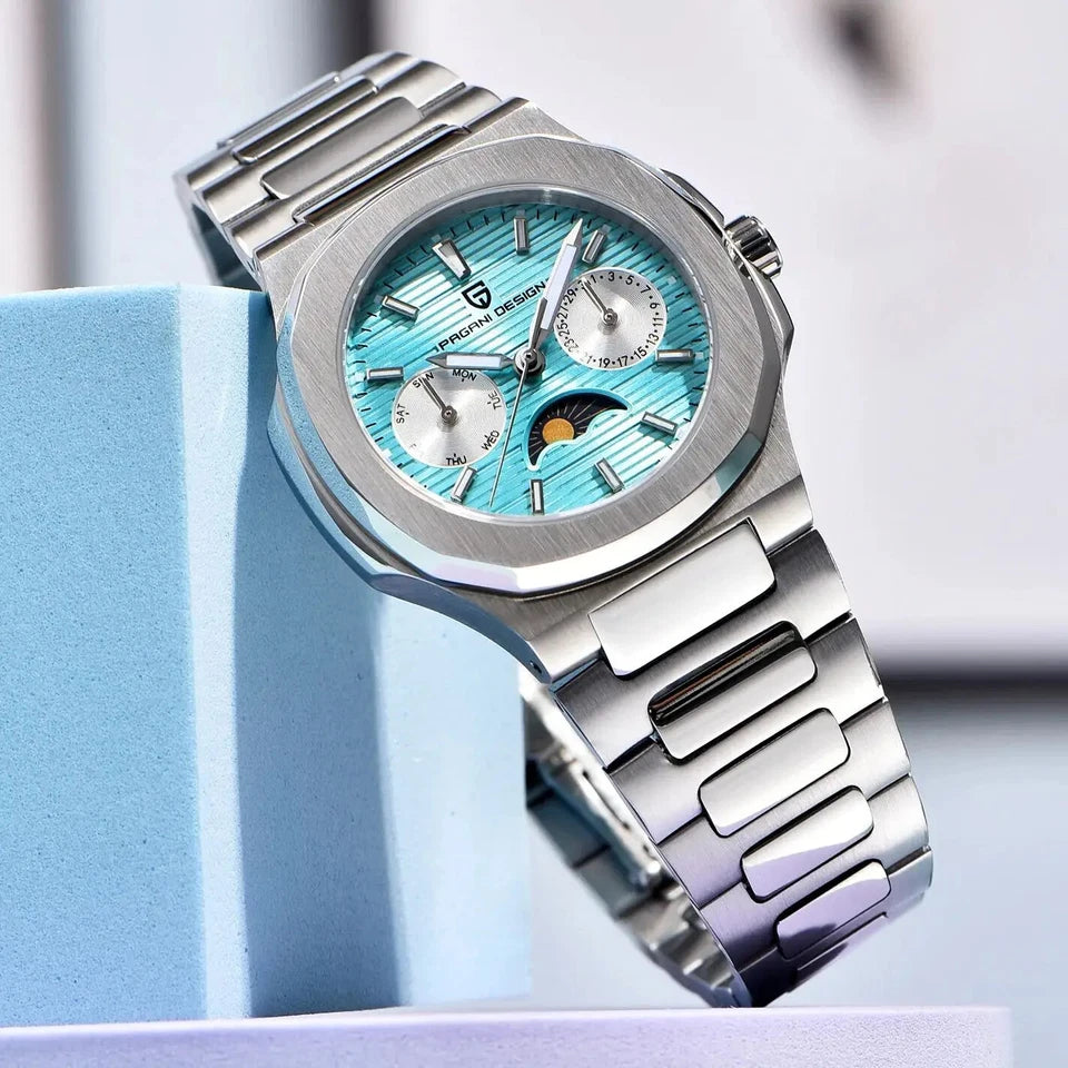 Lifestyle image of Pagani Design PD-1786 quartz chronograph watch with blue dial and moonphase subdial, stainless steel bracelet and silver case, displayed on blue geometric blocks with a blurred background.