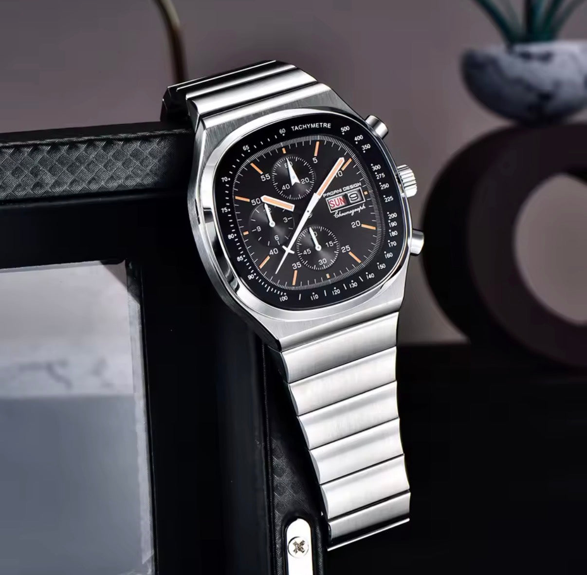 Pagani Design PD-1819 black dial chronograph propped on a shelf beside a picture frame