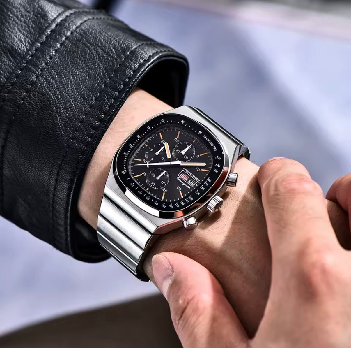 Pagani Design PD-1819 black chronograph worn on a wrist with a leather jacket sleeve