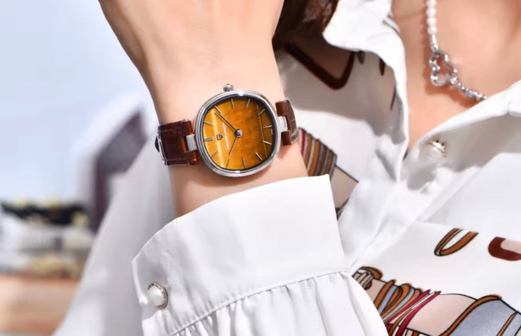 Pagani Design PD-1825 brown tiger's eye model worn on a wrist with a white blouse