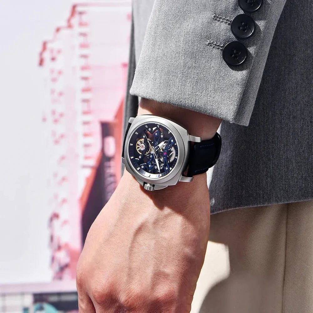 Pagani Design PD-YS017 blue skeleton watch worn on wrist with a grey suit sleeve