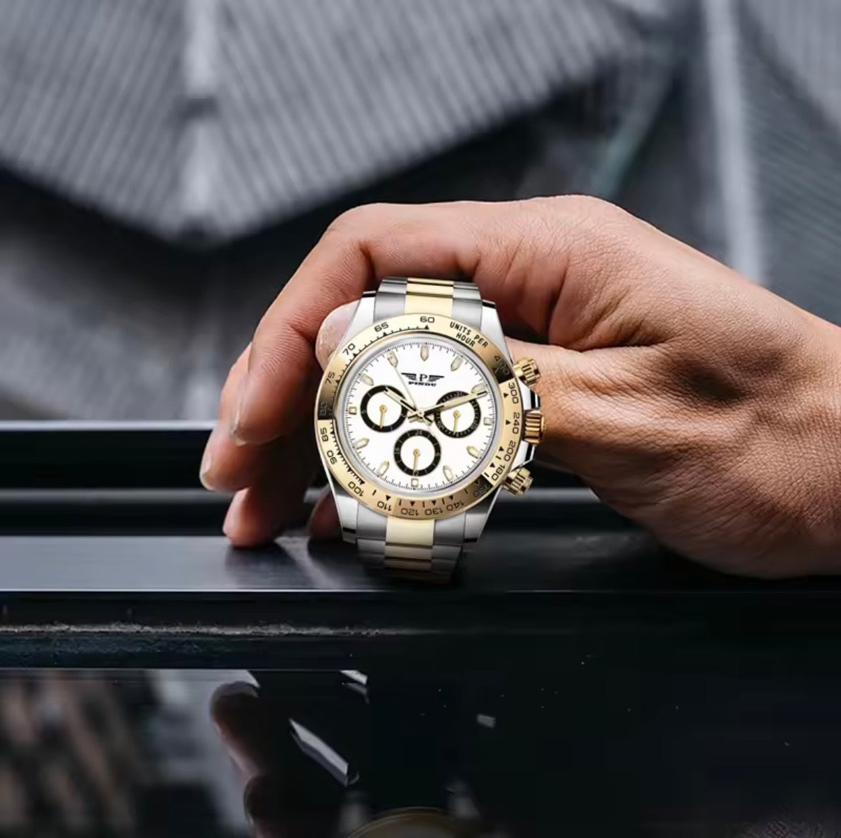 PINDU P6589 white dial two-tone chronograph held in hand on a rooftop railing