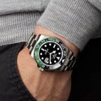 PINDU PD6510 GMT automatic watch with black dial and green-black bezel worn on wrist with grey sweater