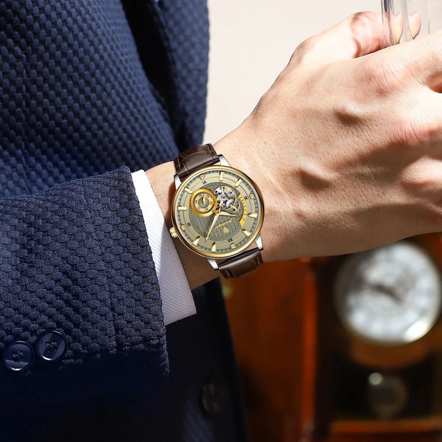 POEDAGAR 1416 tourbillon watch with gold dial and brown leather strap on wrist with navy suit