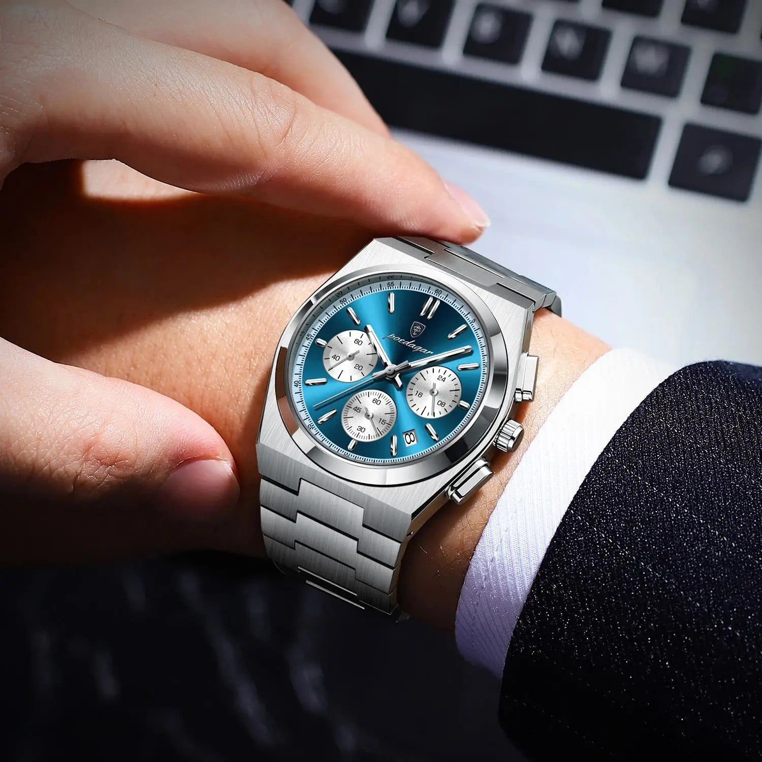 POEDAGAR 970 men's quartz chronograph watch with blue dial and steel bracelet on wrist near laptop