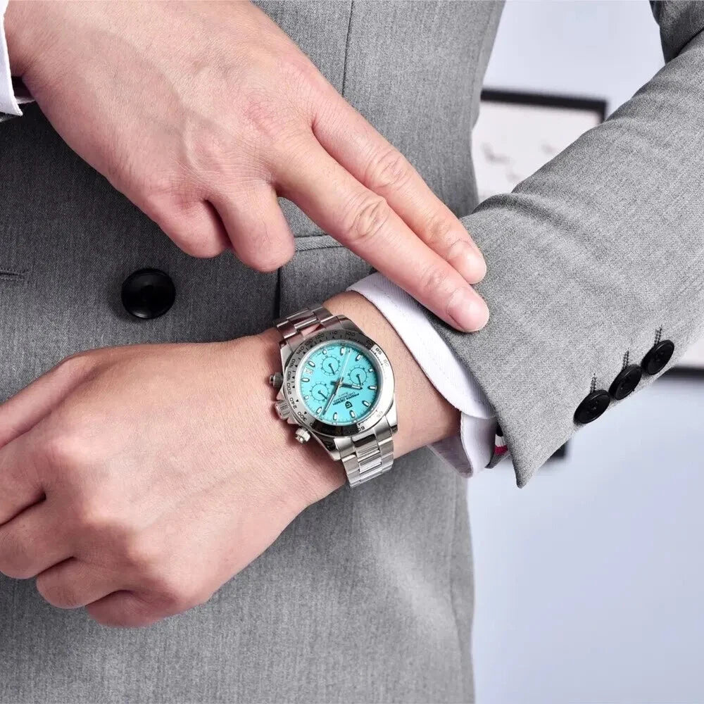 Person wearing a watch with a turquoise face and silver case, adjusting it on their wrist.