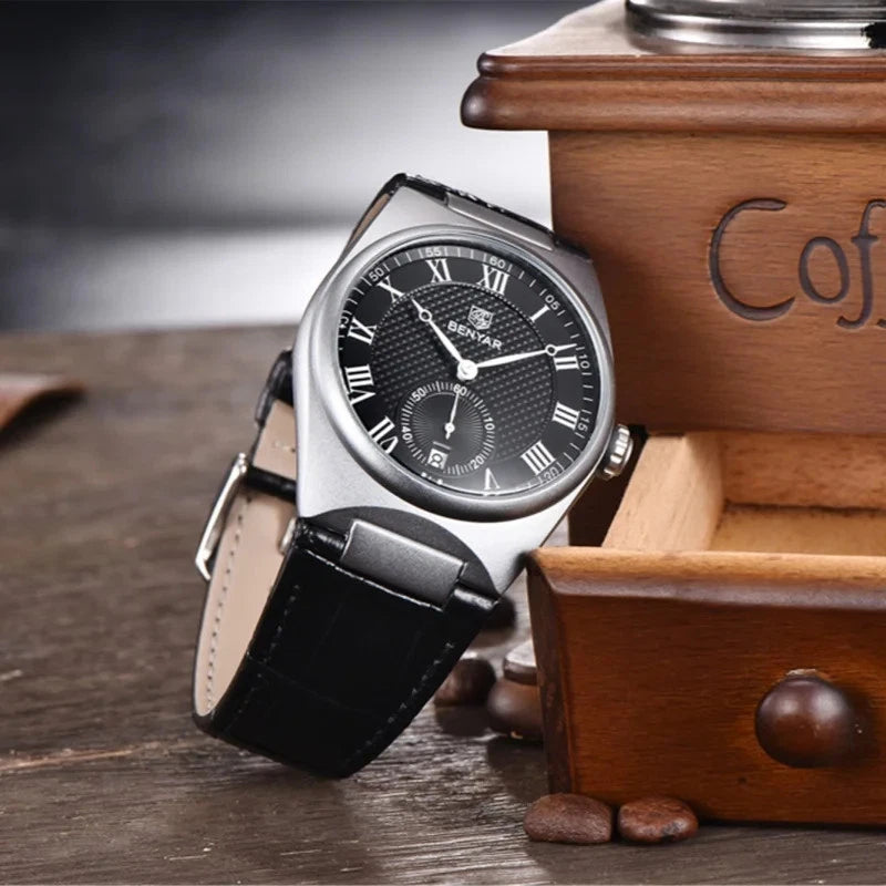 Wristwatch with black leather strap and silver case on a wooden surface with coffee beans.