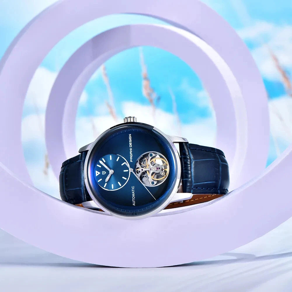 Luxury watch with blue face and black strap on a light blue background