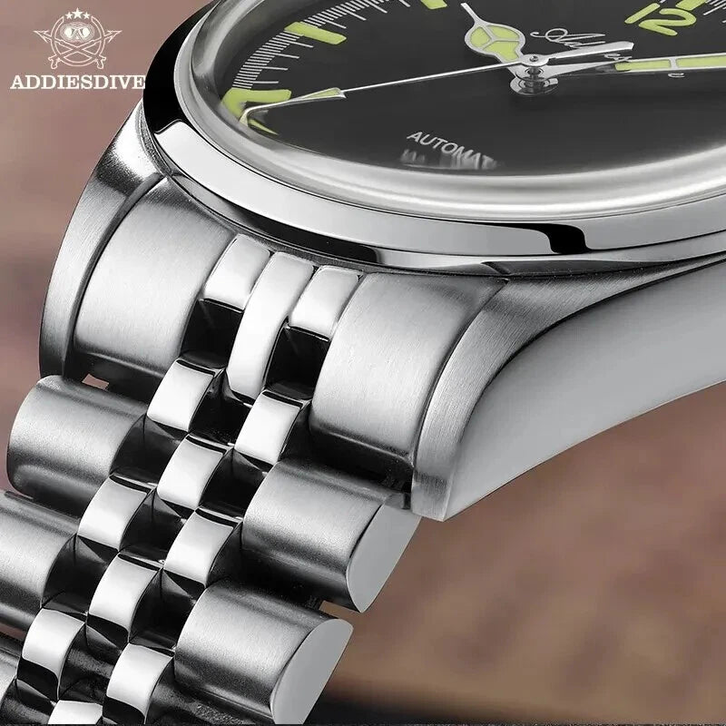 Close-up of a silver watch with a black face and green accents, featuring the brand 'ADDIESDIVE'.