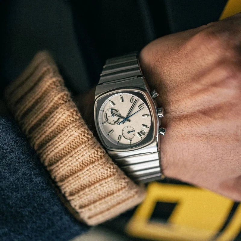 Close-up of a person wearing a silver watch with a detailed face on their wrist.