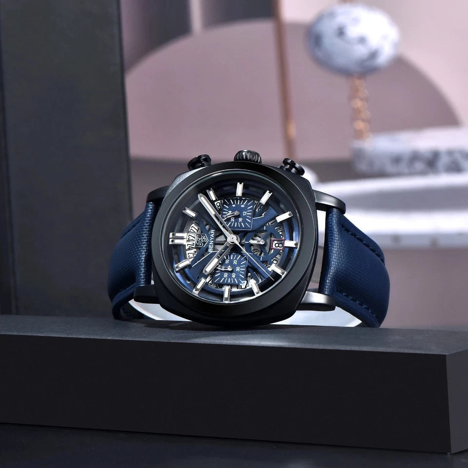 Luxury watch with blue strap on a black stand against a blurred background