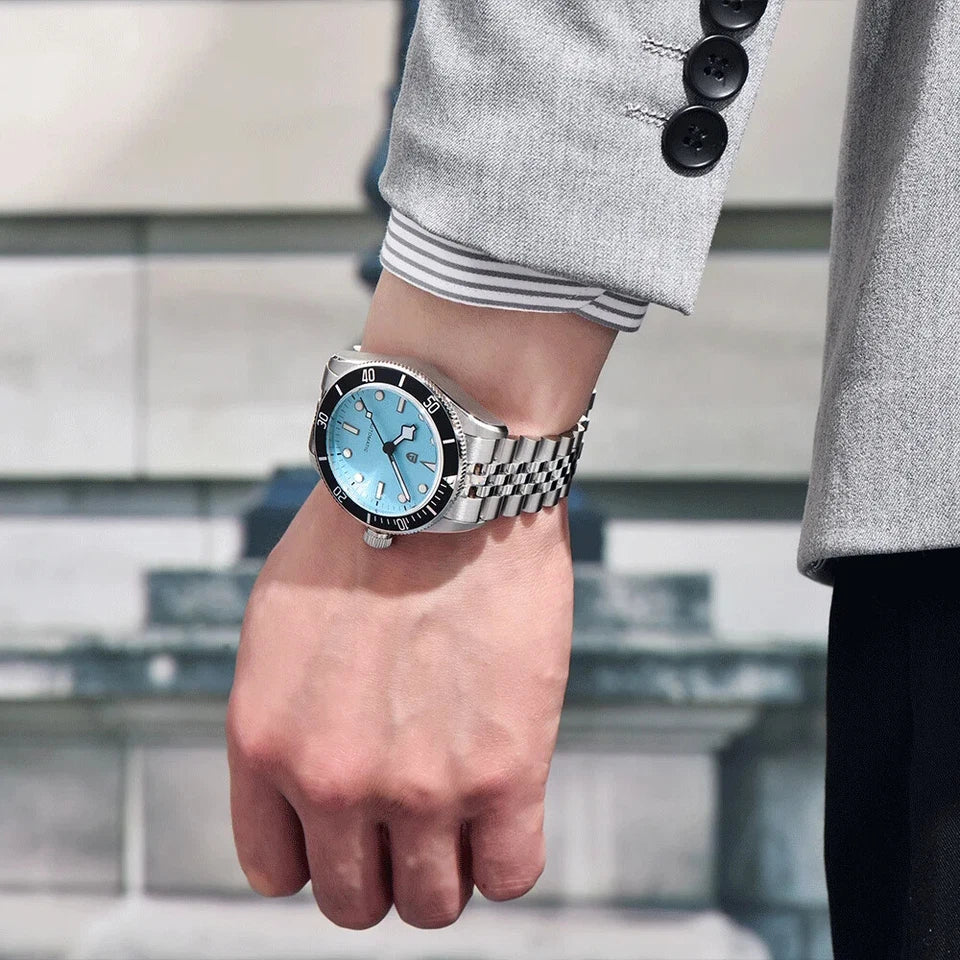 Hand wearing a silver watch with a blue face, blurred background