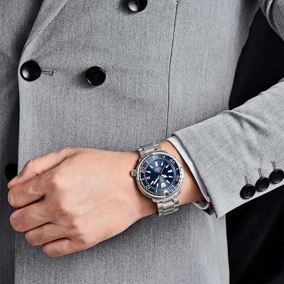 Person wearing a silver watch with a blue face on a gray coat background