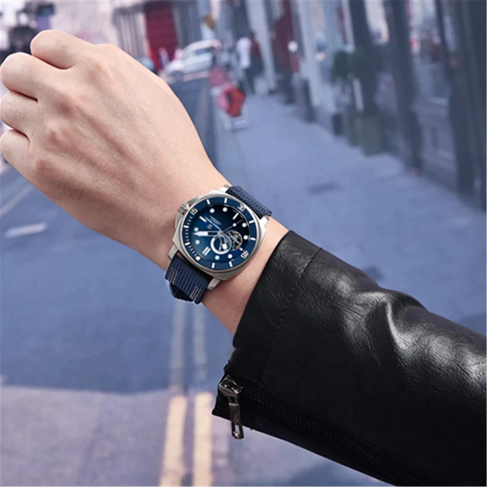 Hand wearing a watch with a blurred street scene in the background