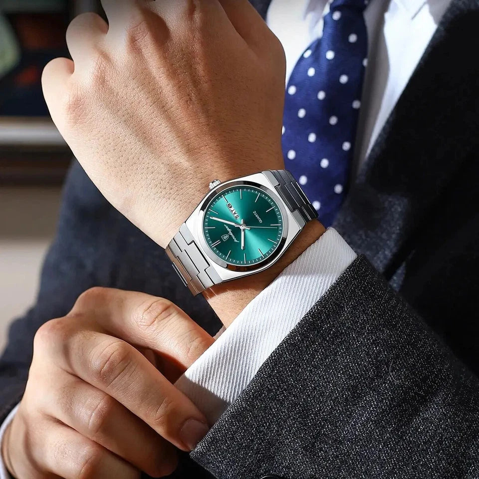 Close-up of a person wearing a silver watch with a green face, adjusting their suit jacket.
