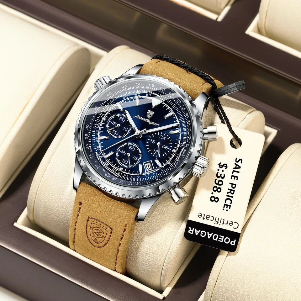 Watch with brown leather strap and blue face in a box, tag attached, on a beige surface.