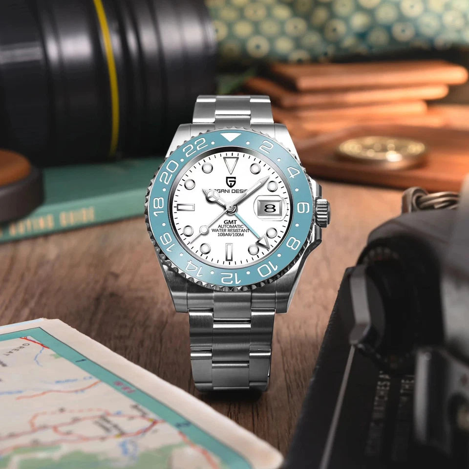 Silver and blue watch on a wooden surface with books and a map in the background