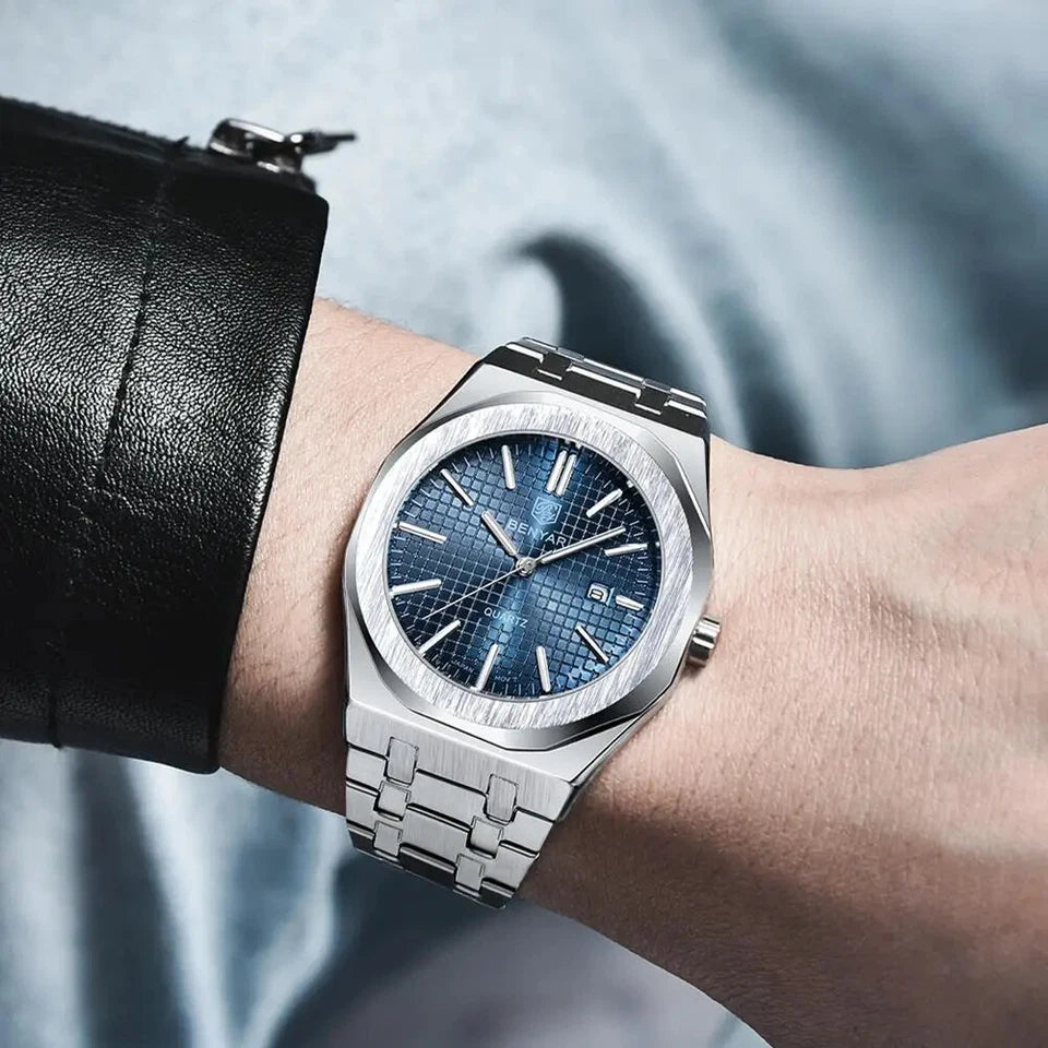 Silver watch with blue face on a wrist against a neutral background