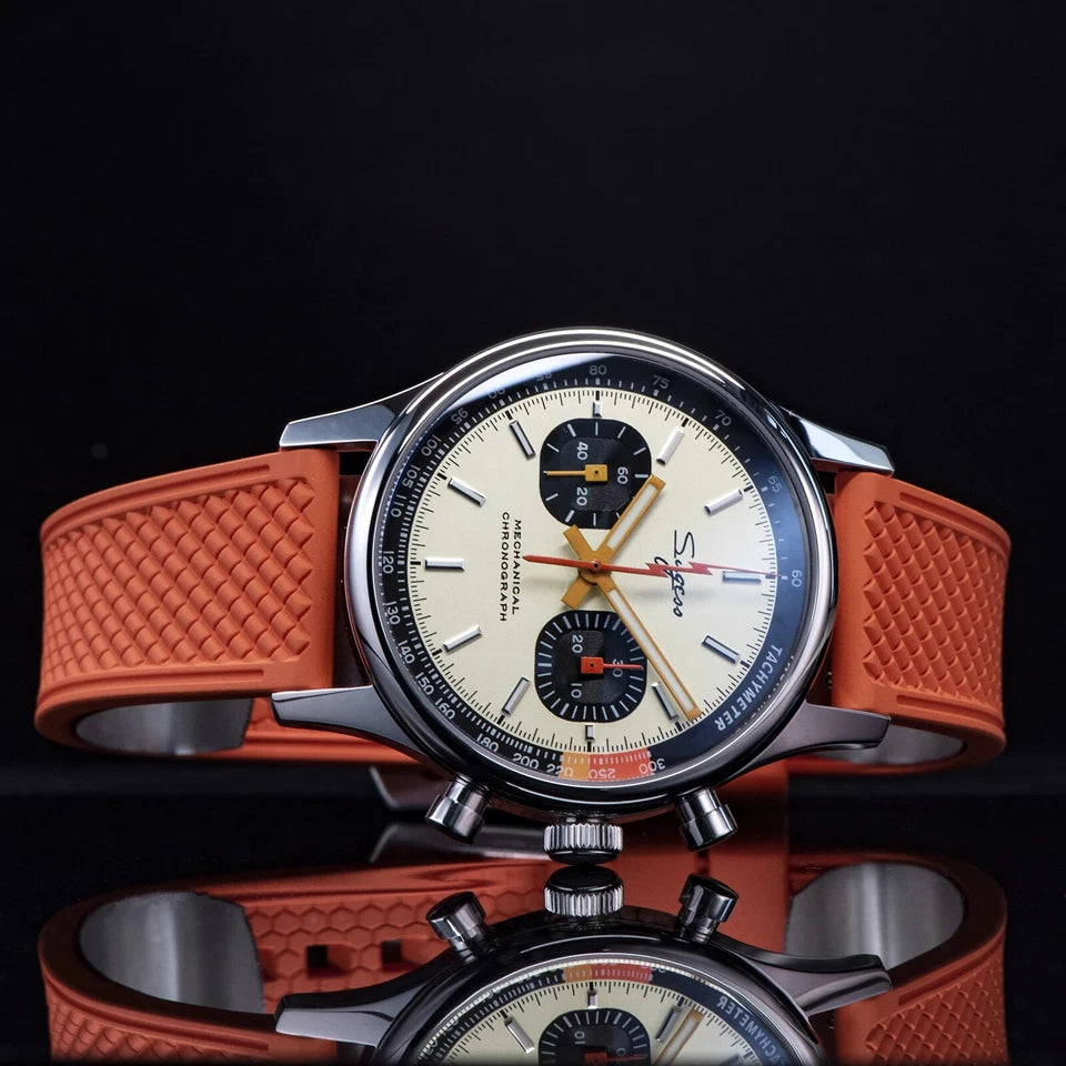 Wristwatch with orange strap on a reflective surface against a black background