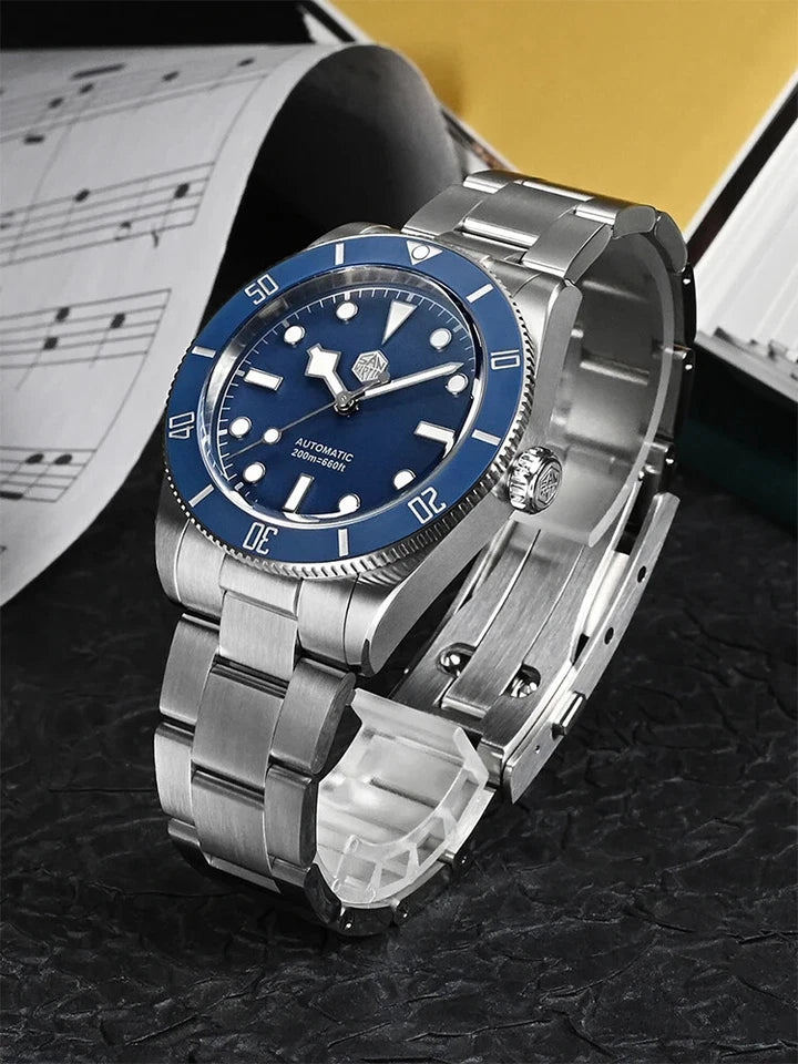 Luxury watch with blue face and silver band on a dark textured surface