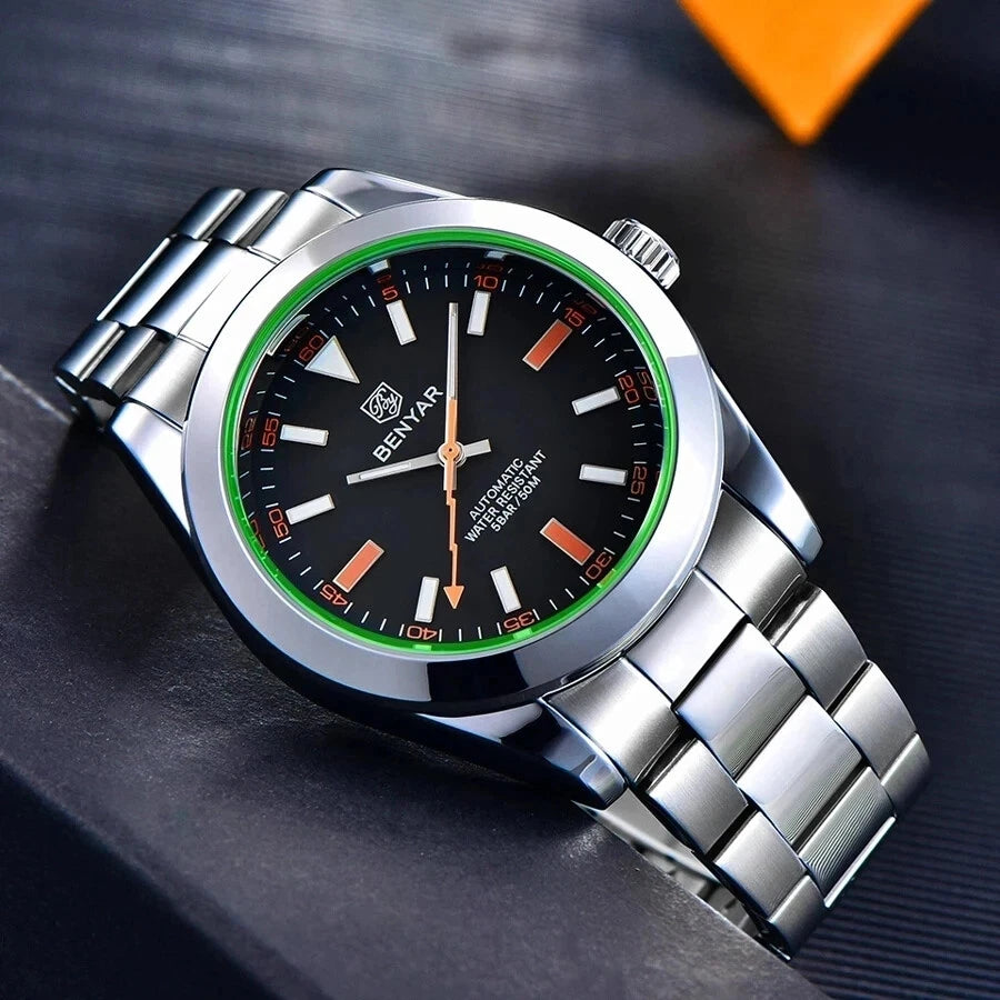 Silver watch with a black face and green accents on a dark surface