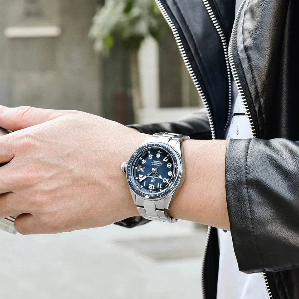 Person wearing a silver watch with a blue face on a blurred background