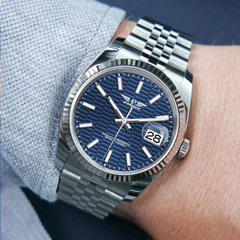 Silver watch with blue dial on a wrist against a light gray fabric background