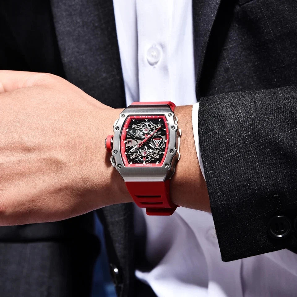 Red and silver watch on a person's wrist with a dark suit and white shirt background