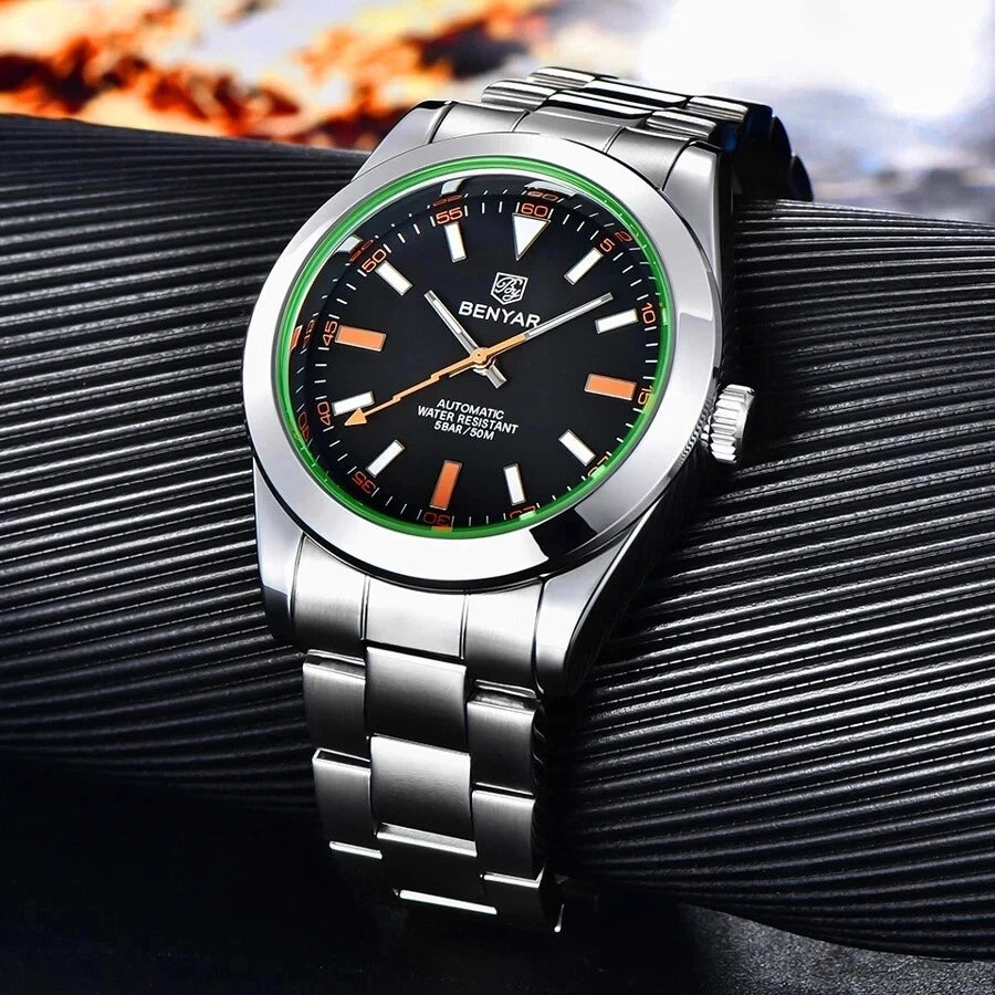 Silver watch with a black and green face on a textured surface