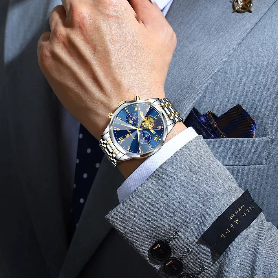 Close-up of a person wearing a luxurious watch on a gray suit with a white shirt.