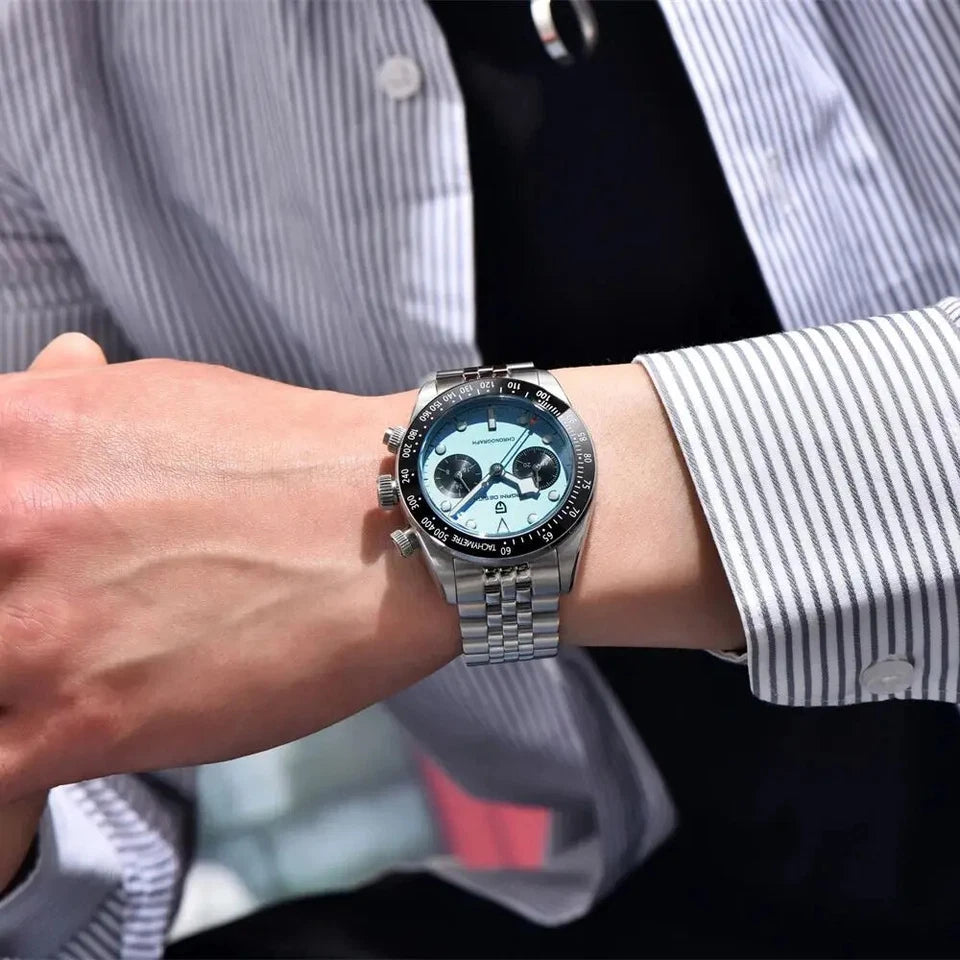 Close-up of a wrist wearing a silver watch with a blue face, against a blurred background.