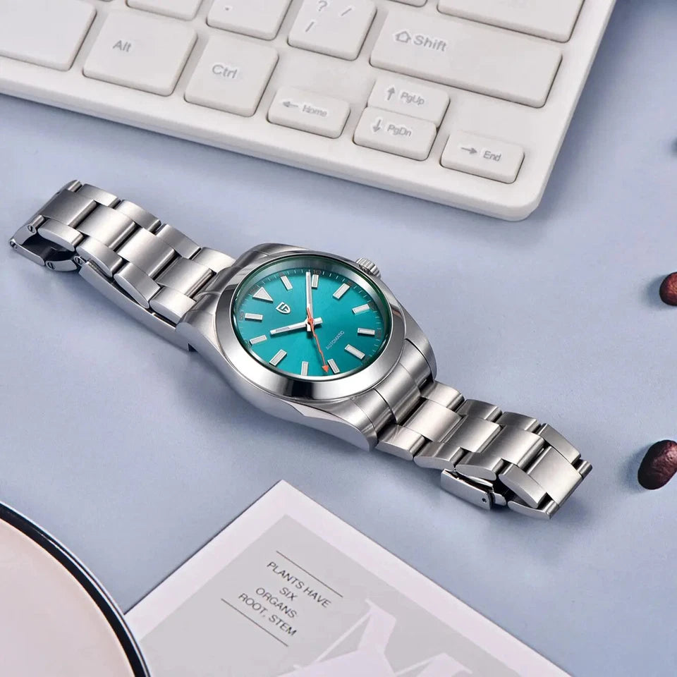 Silver watch with a turquoise face on a light gray surface with a keyboard in the background