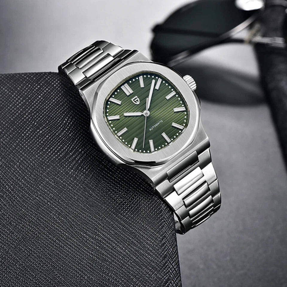 Silver watch with a green face on a dark textured surface
