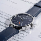 Seestern S382 navy blue dress watch on blue leather strap on printed paper, lifestyle flat lay