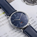 Seestern S382 navy blue dress watch on blue leather strap resting on a printed magazine, flat lay