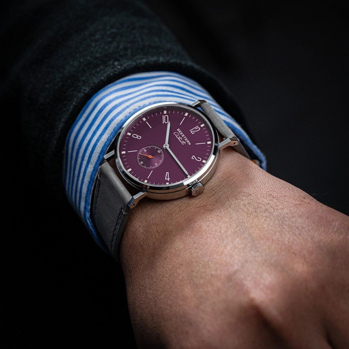 Seestern S382 purple dial dress watch on grey suede strap worn on the wrist, close-up lifestyle
