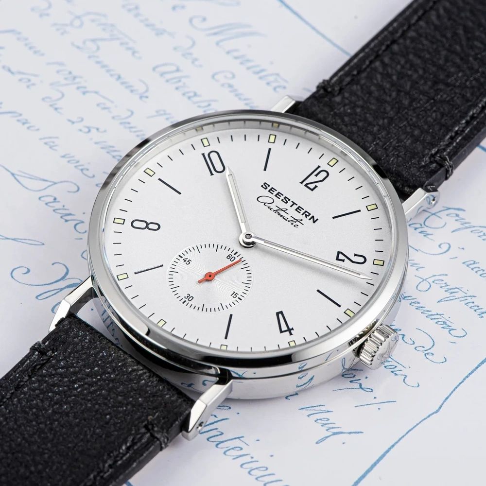 Seestern S382 silver-white dial dress watch on black leather strap on script paper, flat lay