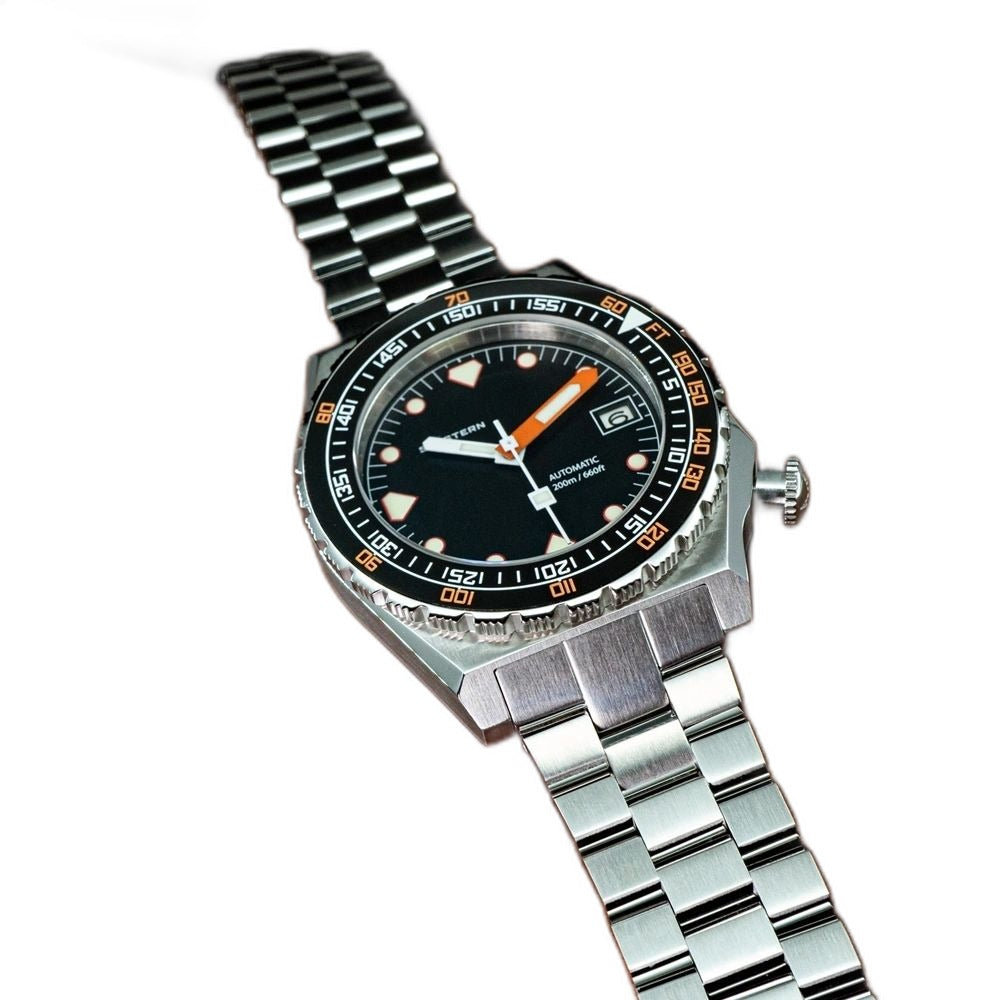 Seestern S407 black ceramic diver on steel bracelet resting on brown leather, angled view