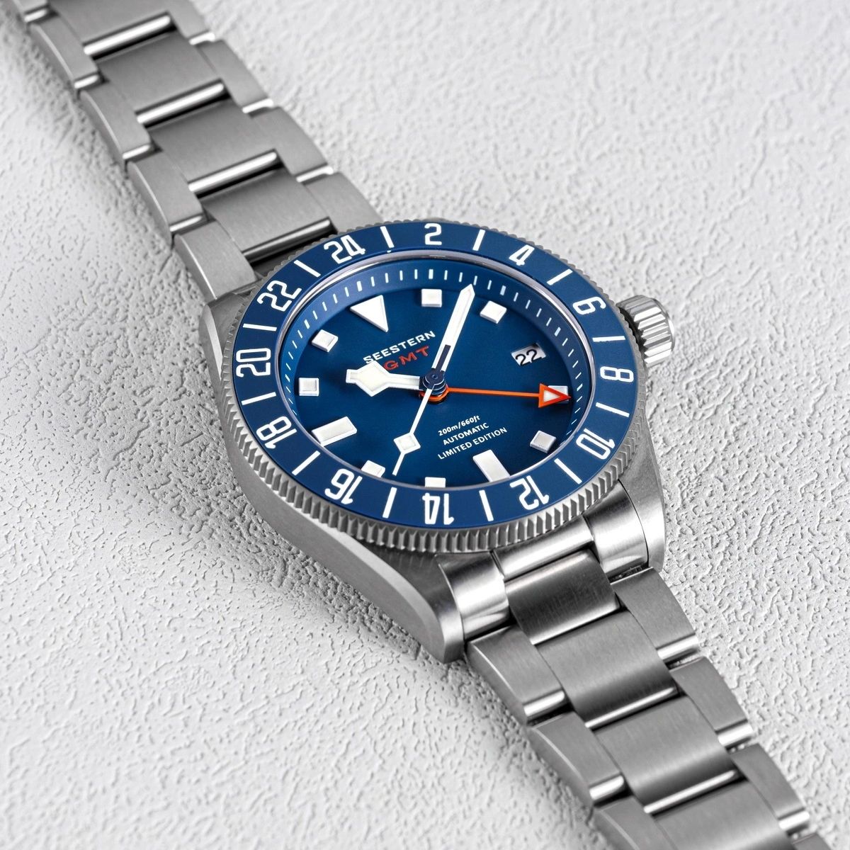 Seestern S462 titanium GMT, blue dial, angled view on white textured surface, steel bracelet